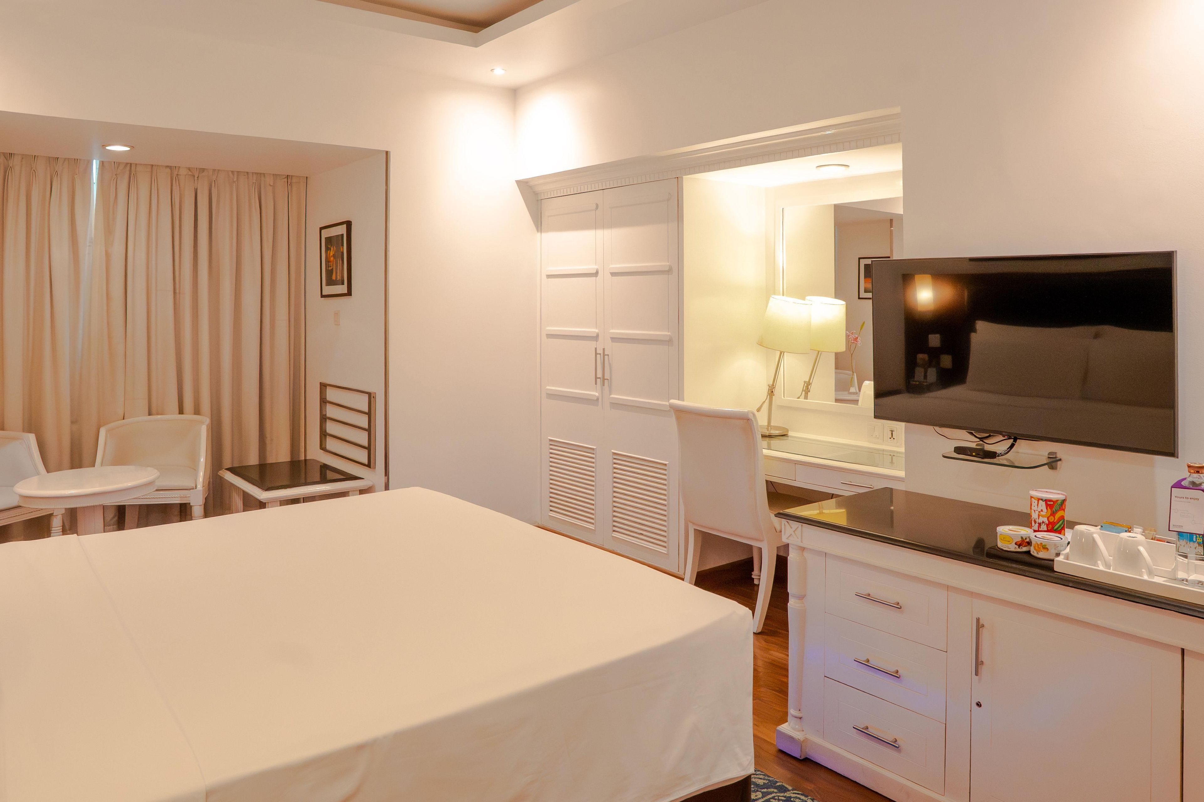 Een hotelkamer met een bed, een bureau, een stoel, een televisie en een minibar.