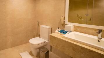 A modern bathroom with a toilet, bidet, and a sink with a mirror.
