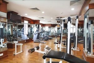 A gym with various exercise equipment, including treadmills, weight machines, and free weights.