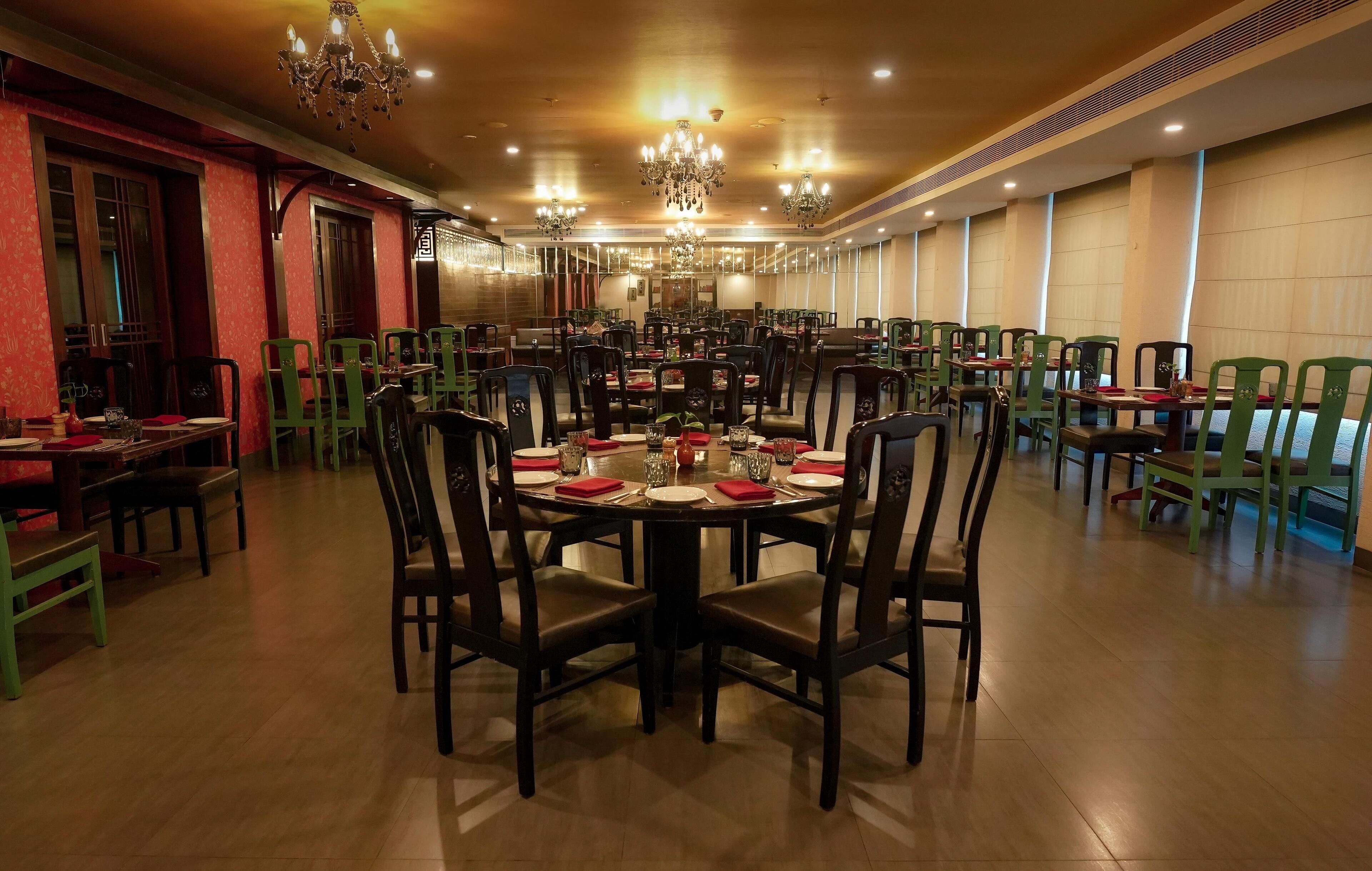 Un comedor amplio con varias mesas y sillas, candelabros y un cálido suelo de madera.