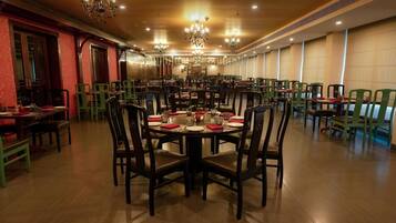 Un comedor amplio con varias mesas y sillas, candelabros y un cálido suelo de madera.