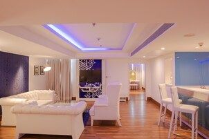Una sala de estar moderna con un sofá, una silla y una zona de bar con taburetes.