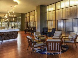 A lobby with a reception desk, seating area, and a large window with a textured design.