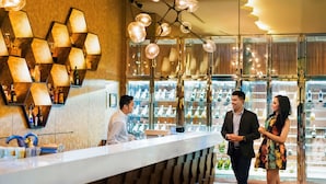 Un espace d’accueil d’hôtel au design moderne, comprenant un luminaire hexagonal et un comptoir doté d’un panneau arrière à motifs.