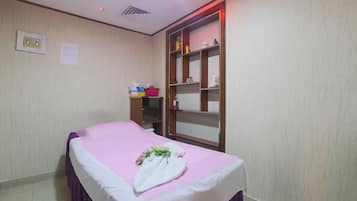 A neatly arranged room with a bed, a shelf with toiletries, and a wall-mounted light fixture.