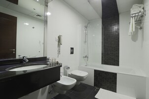 Un baño moderno con lavamanos de encimera negro, inodoro blanco y cabina de ducha con mampara de vidrio.