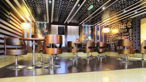 A modern bar area with multiple stools and a wall with coffee-related words. - Queen Palace Hotel (Abu Dhabi)