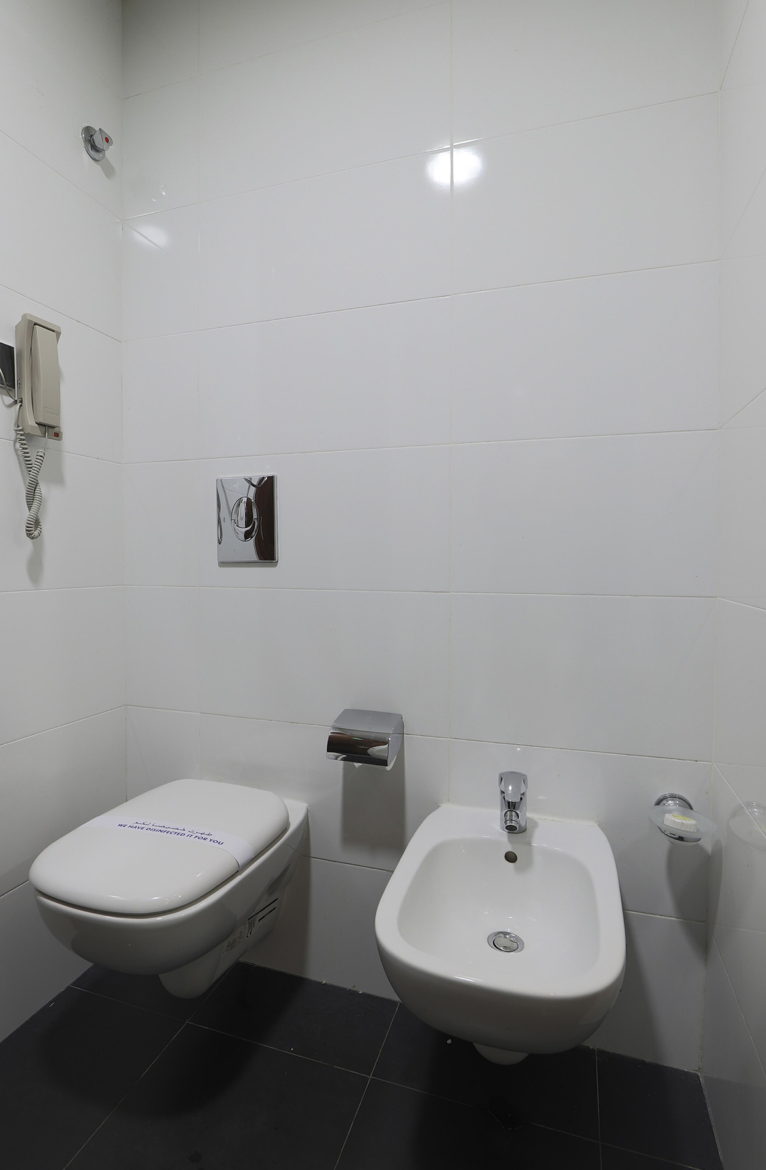 Une salle de bain équipée de toilettes, d’un bidet et d’un sèche-mains.