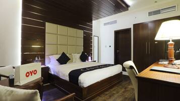 Een hotelkamer met een bed, een bureau, een stoel, een kledingkast en een nachtkastje.