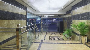 A marble-floored lobby with a glass railing, a chandelier, and potted plants. - Queen Palace Hotel (Abu Dhabi)