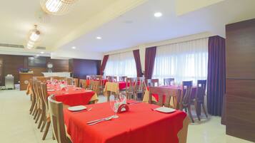 A dining area with multiple tables set for service, wooden chairs, and a clock on the wall.