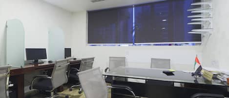 Una sala conferenze con un lungo tavolo, diverse sedie, un'ampia finestra e una bandiera sul tavolo.