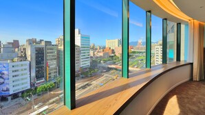 Een moderne hotelkamer met grote ramen en uitzicht over de stad.