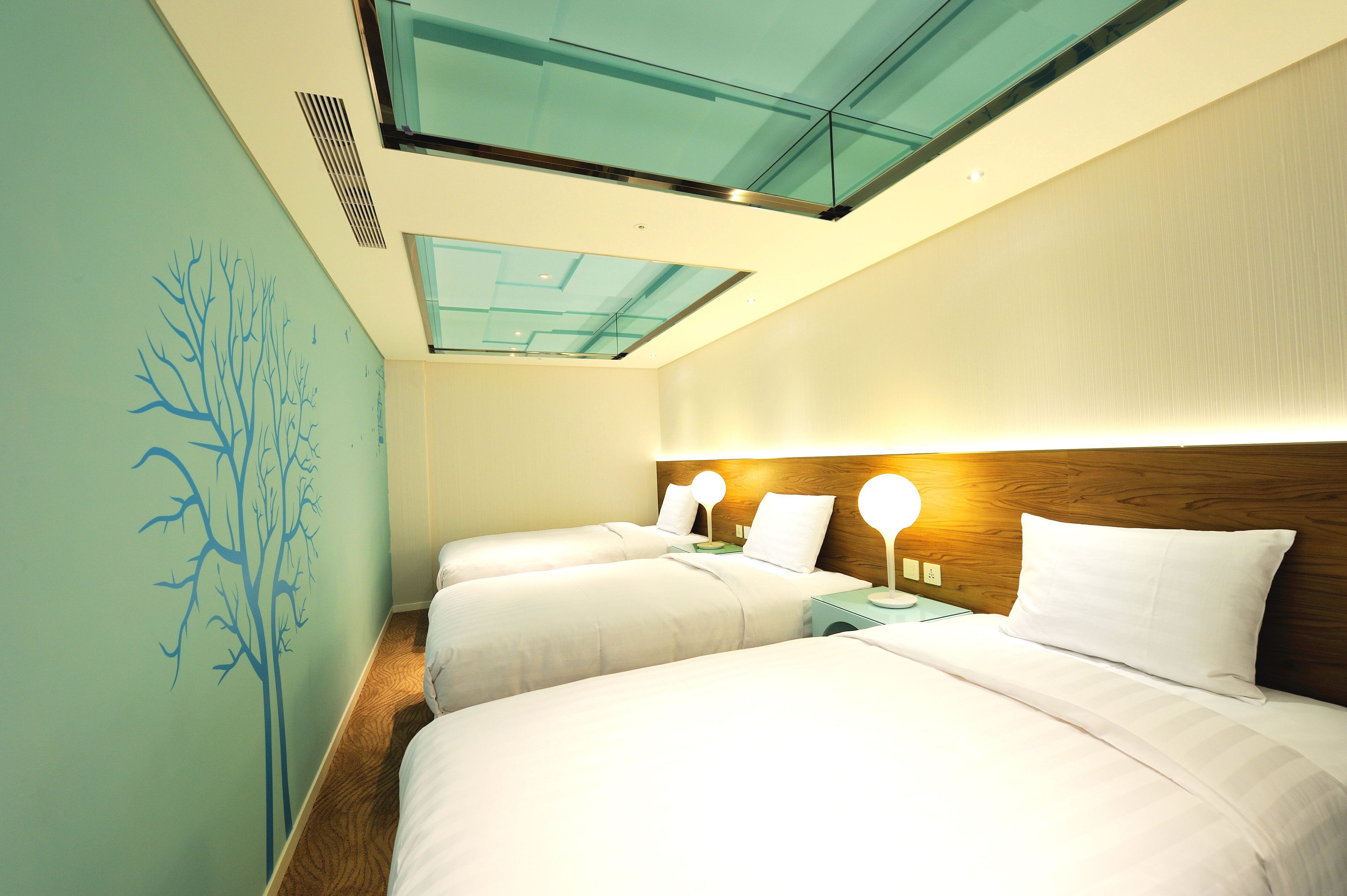 A hotel room with two beds, a wooden headboard, a glass ceiling, and a wall mural.