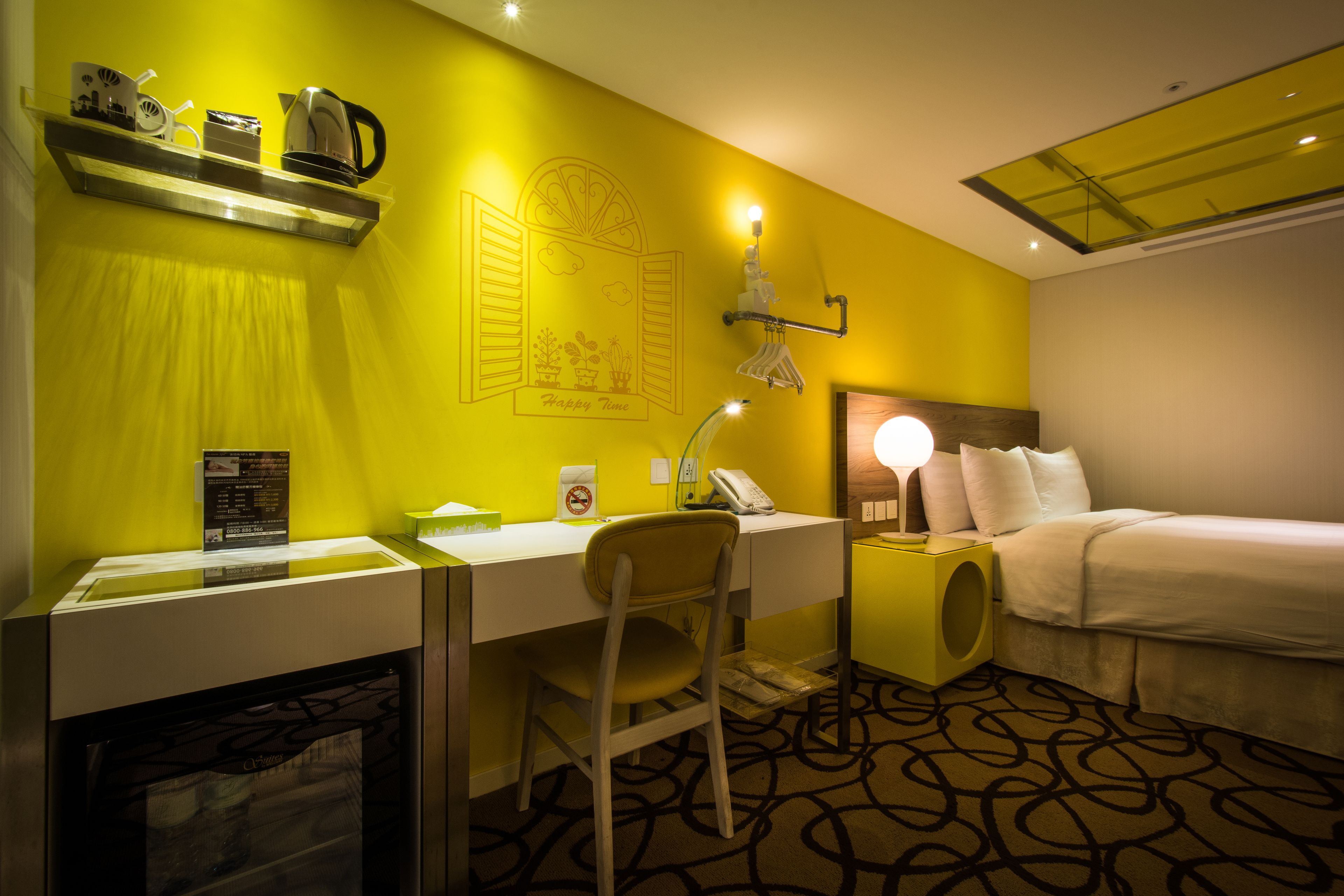 A hotel room with a desk, chair, bed, and a small washbasin.