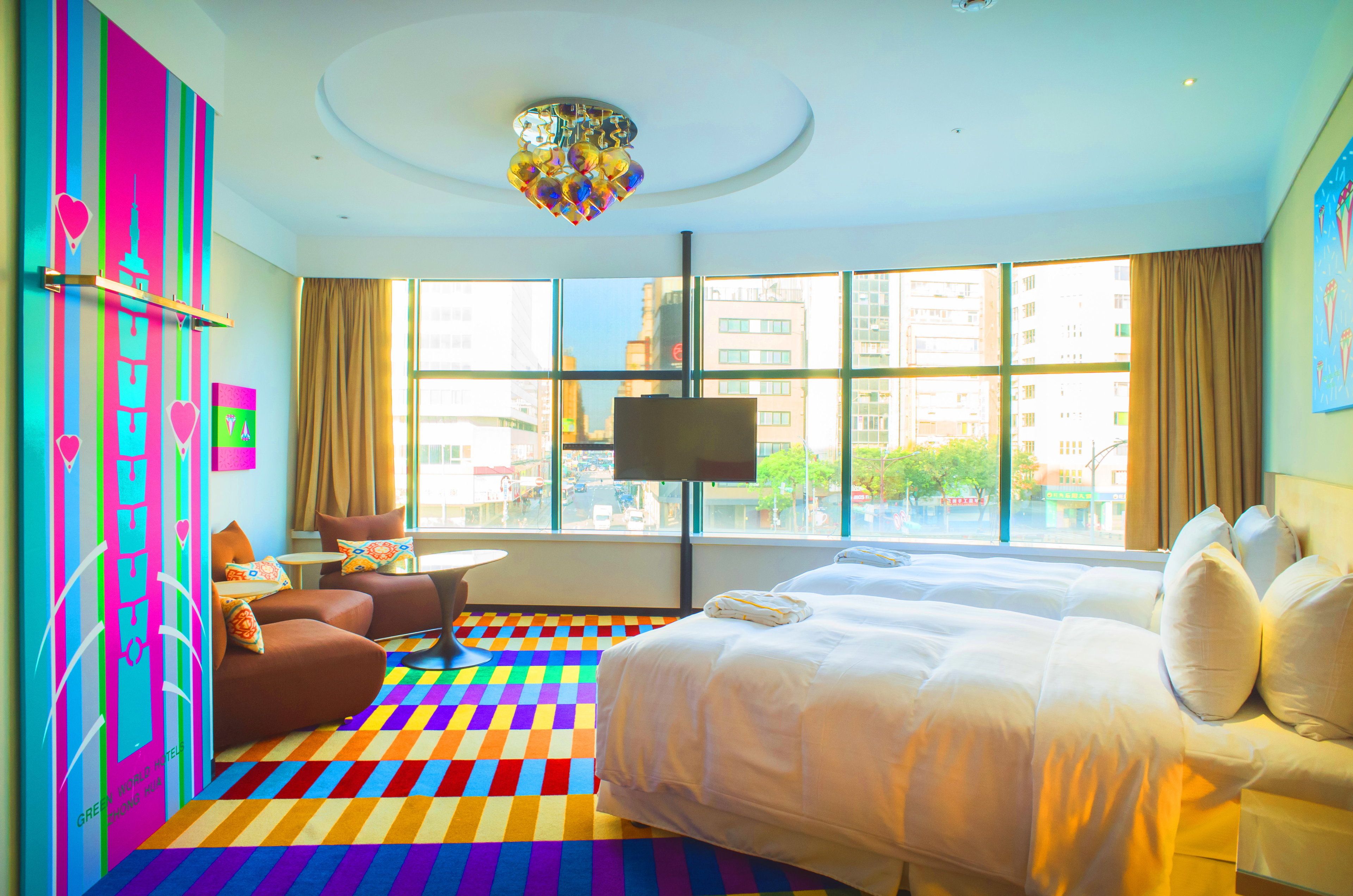 A hotel room with a large bed, a sofa, a small table, and a TV.