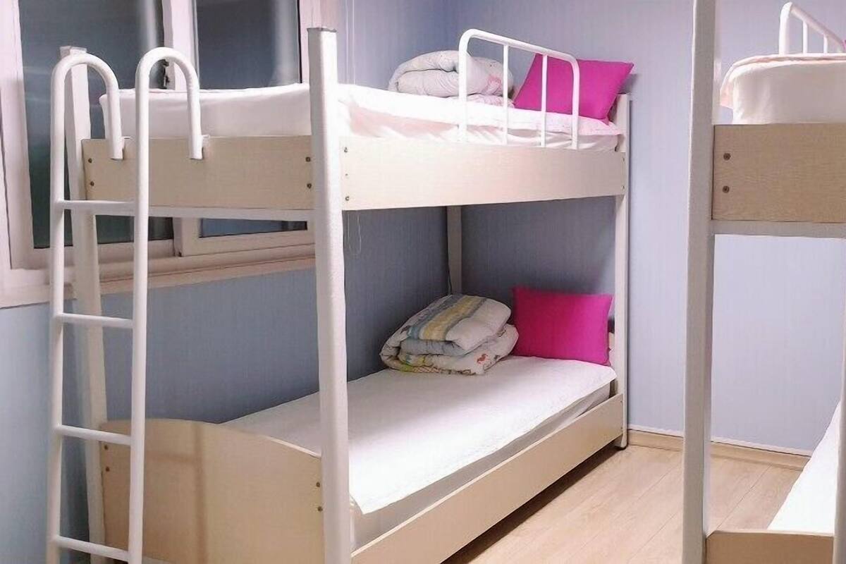 A bunk bed room with two levels, each with a mattress and pillows.