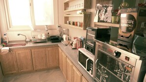 A kitchen with wooden cabinets, a sink, a microwave, and a coffee machine. - Beluga Guest House - Hostel (Yeosu)