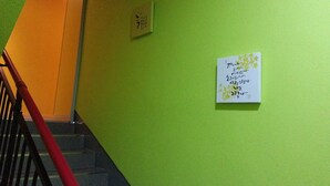 A staircase with a red handrail leading to a room with green walls. - Beluga Guest House - Hostel (Yeosu)