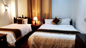 Deux lits simples avec des têtes de lit en bois, une table de chevet avec une lampe et un luminaire fixé au mur.