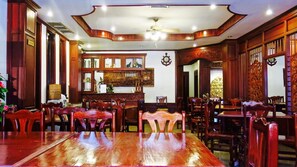A spacious dining area with wooden furniture and a large central table. - Khampiane Boutique Hotel (Vientiane)