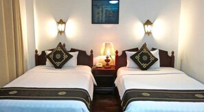 A hotel room with two single beds, each with a decorative pillow and a nightstand with a lamp. - Khampiane Boutique Hotel (Vientiane)