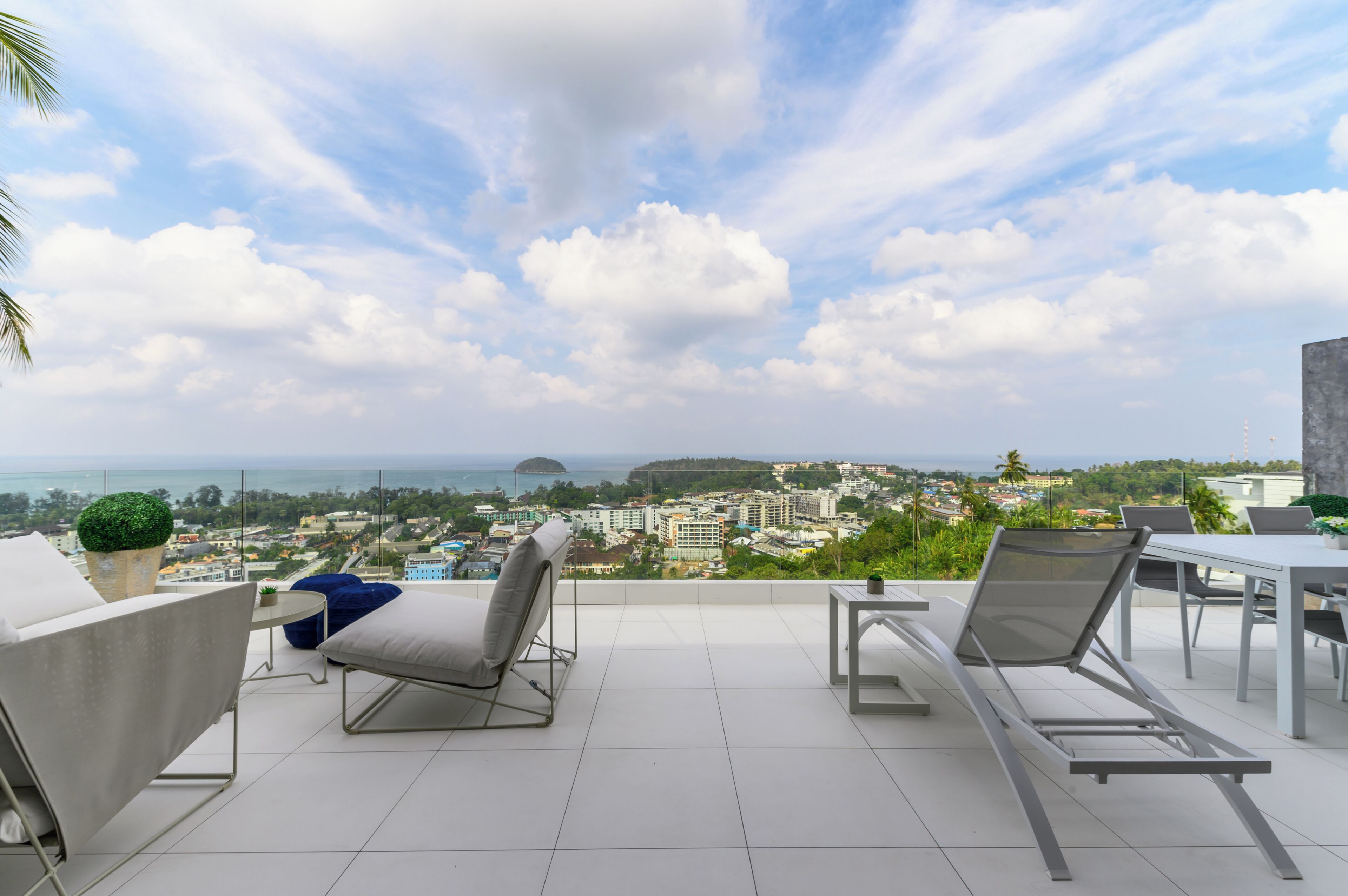 Eine Terrasse mit zwei Liegestühlen, einem kleinen Tisch und einem Blumentopf.