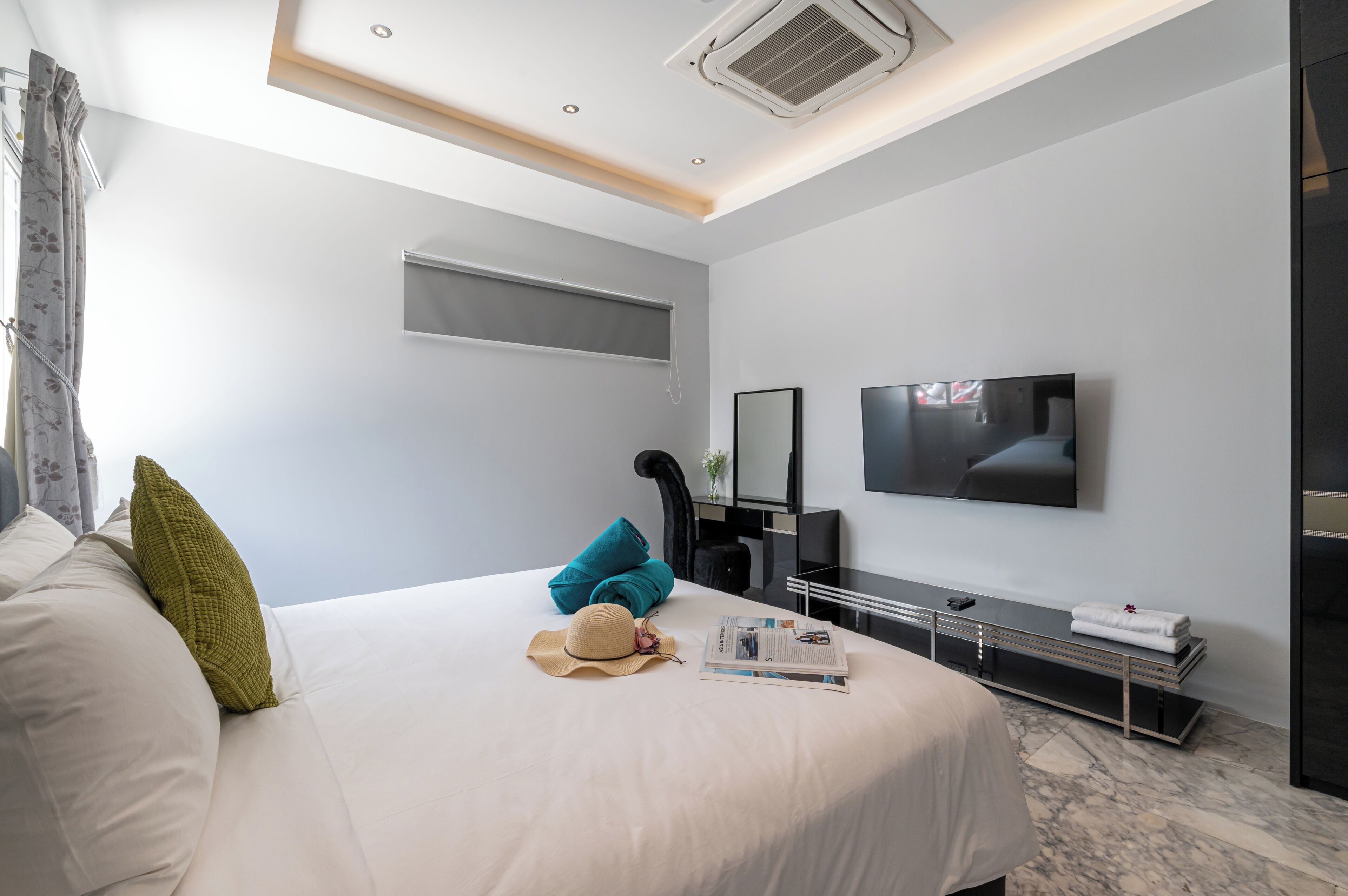 A modern hotel room with a large bed, a flat-screen TV, a desk, and a ceiling fan.