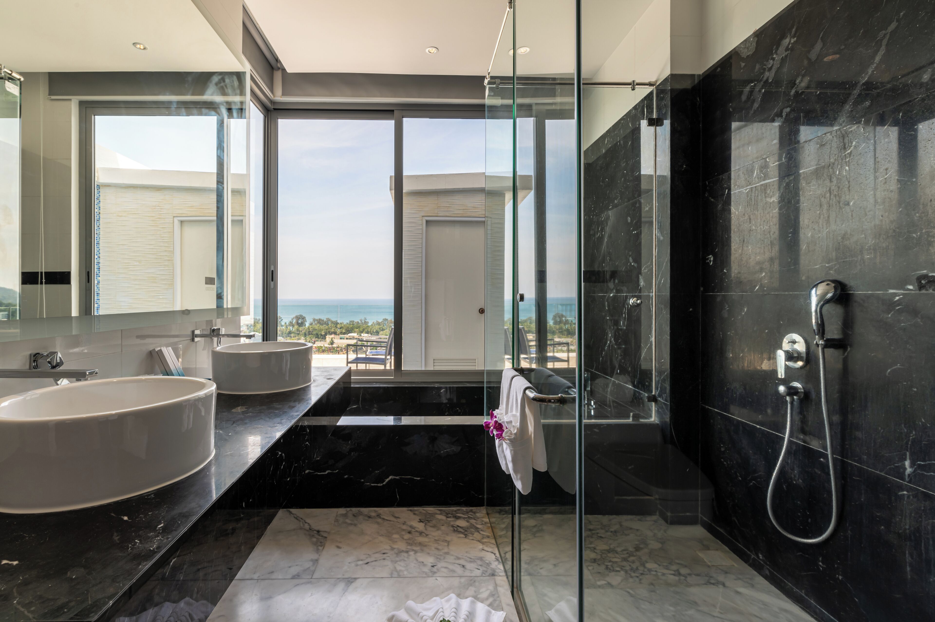 A modern bathroom with a large bathtub, a separate sink, and a glass-enclosed shower.
