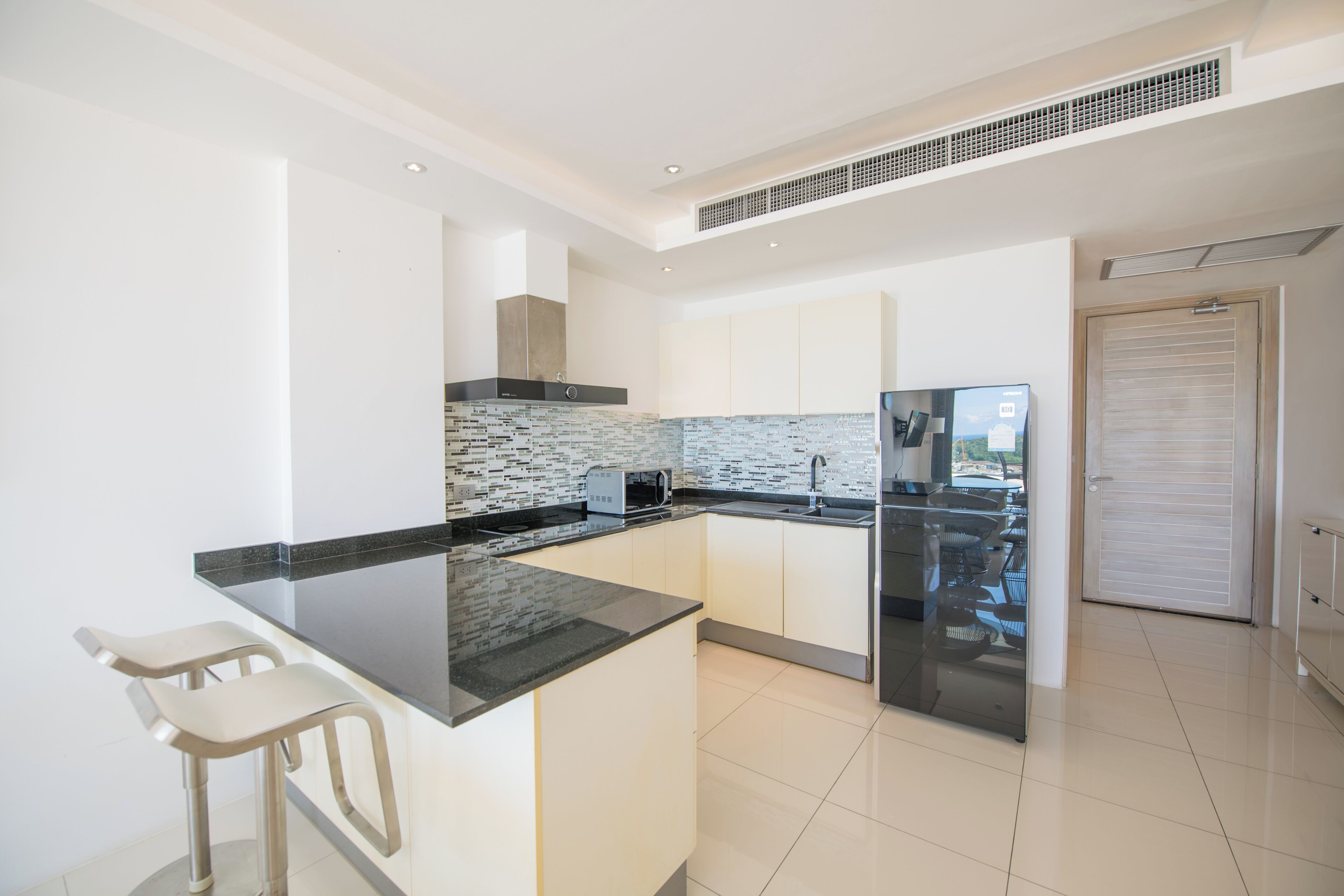 A modern kitchen with a black countertop, white cabinets, and a tiled backsplash.