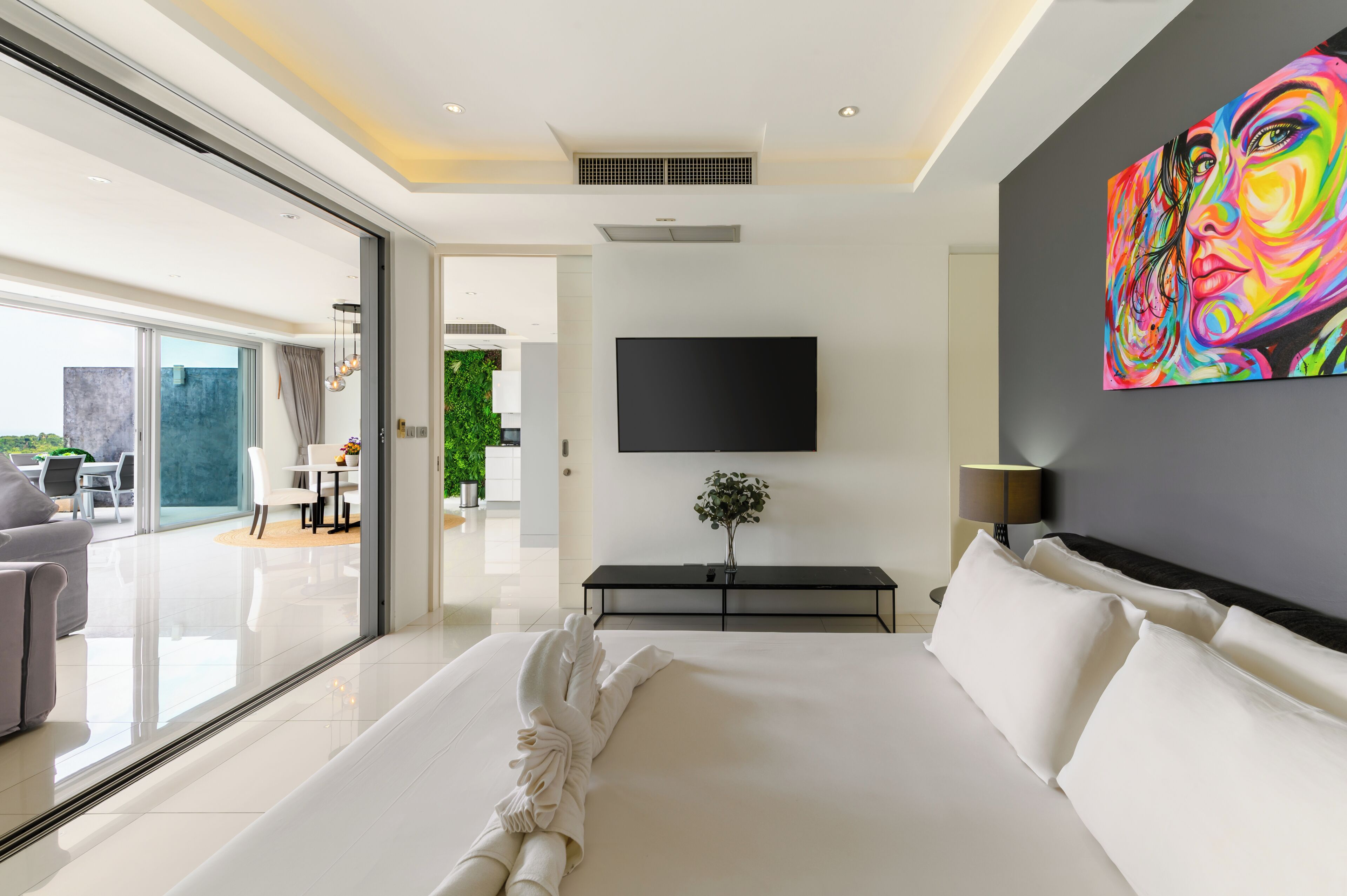 Une chambre d’hôtel moderne avec un grand lit, un téléviseur à écran plat, un tableau au mur et une vue sur l’extérieur.