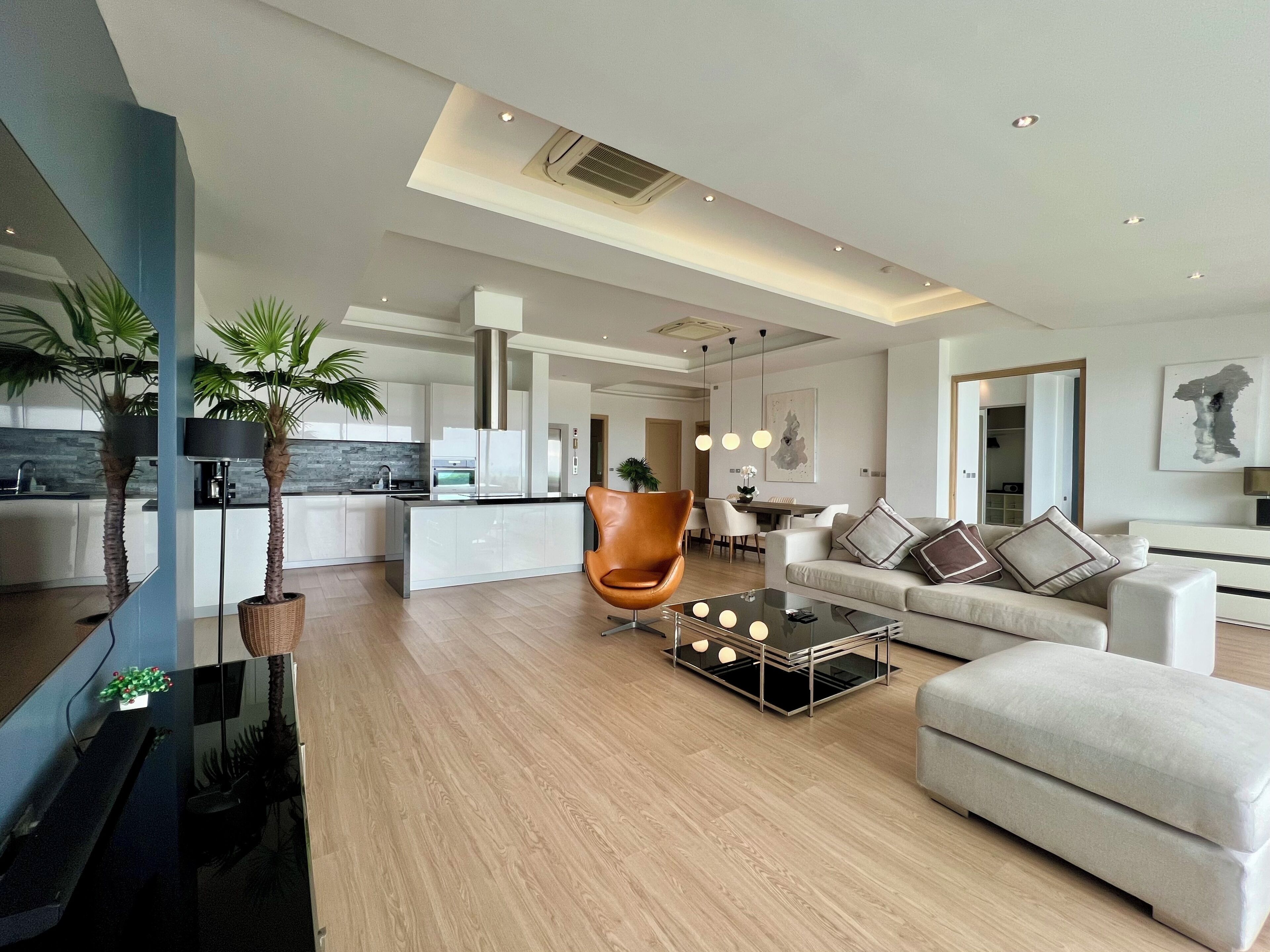 A modern living room with a sofa, coffee table, and a dining area in the background.