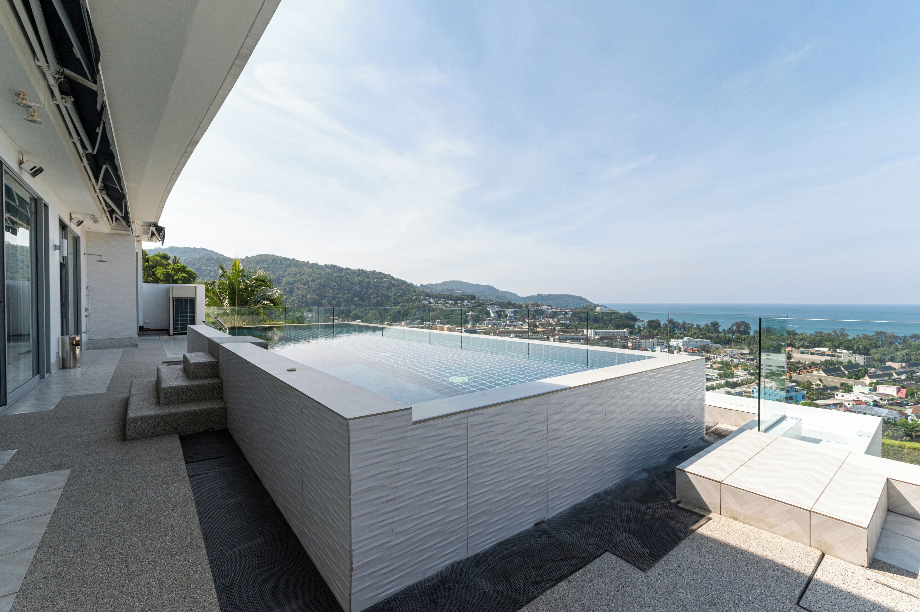 Una piscina infinita moderna con vistas al mar y a las colinas.