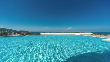 Una piscina cubierta, una piscina al aire libre, sombrillas