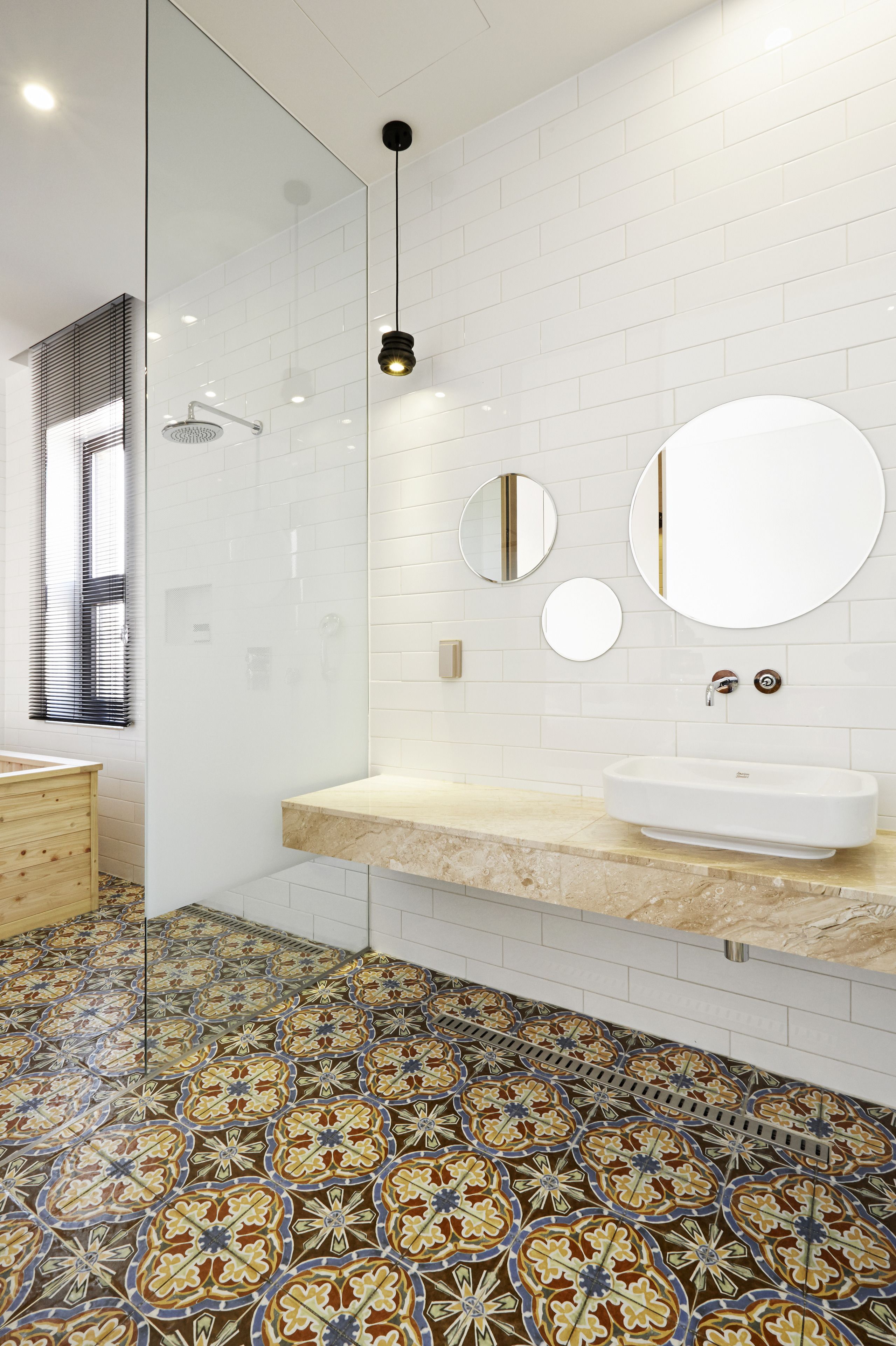 Een moderne badkamer met een glazen douchecabine, een wit wastafelmeubel met een marmeren blad en een vloer met een patroon van tegels.
