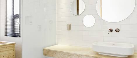 Een moderne badkamer met een glazen douchecabine, een wit wastafelmeubel met een marmeren blad en een vloer met een patroon van tegels.