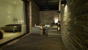 Un área de spa con una terraza de madera, una fuente de piedra y una bañera.