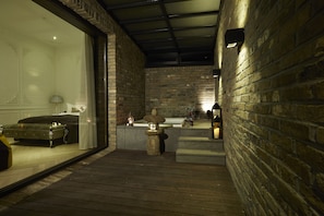 Ein Wellnessbereich mit Holzterrasse, Steinbrunnen und Badewanne.