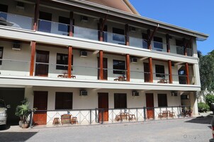 A two-story building with balconies, a covered outdoor seating area, and a garage.