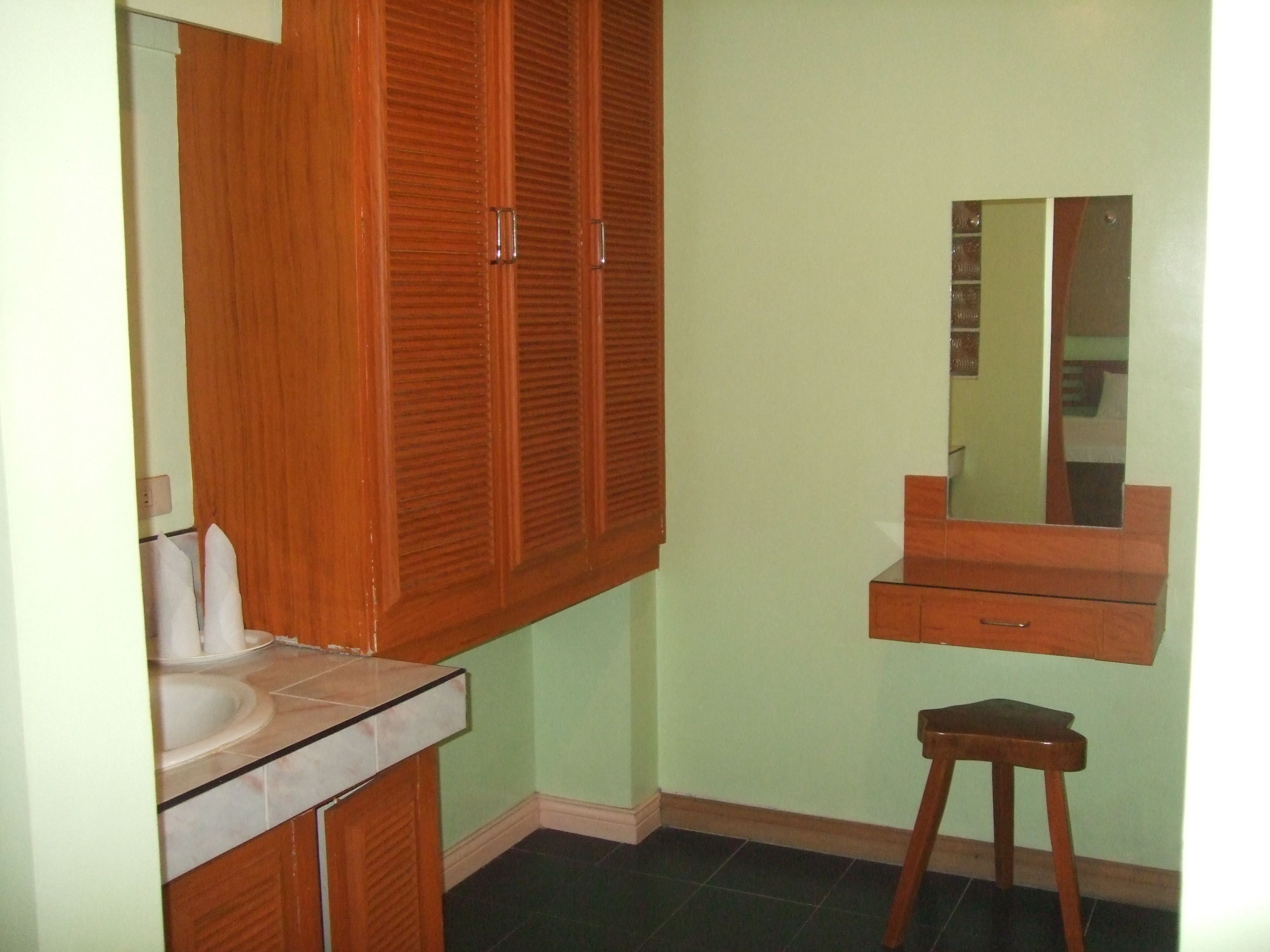 A bathroom with a wooden vanity, a mirror, and a small stool.
