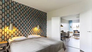 Un moderno cuarto de hotel con papel tapiz estampado, una cama grande, lámparas de noche y vistas al comedor.