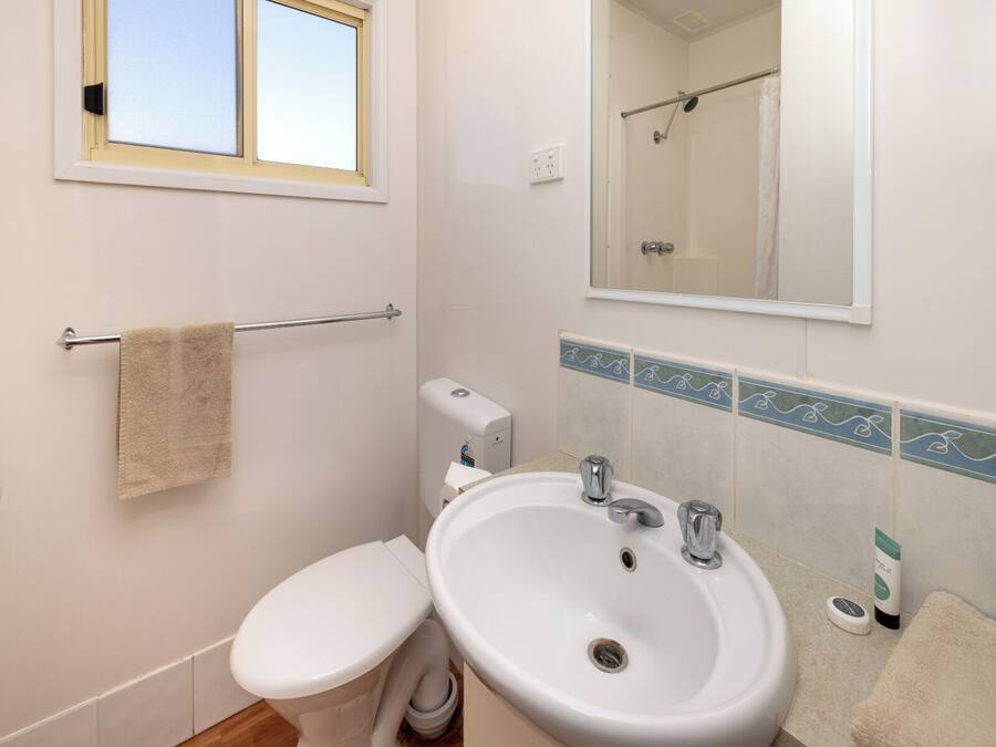 A bathroom with a toilet, sink, towel rack, and a window.