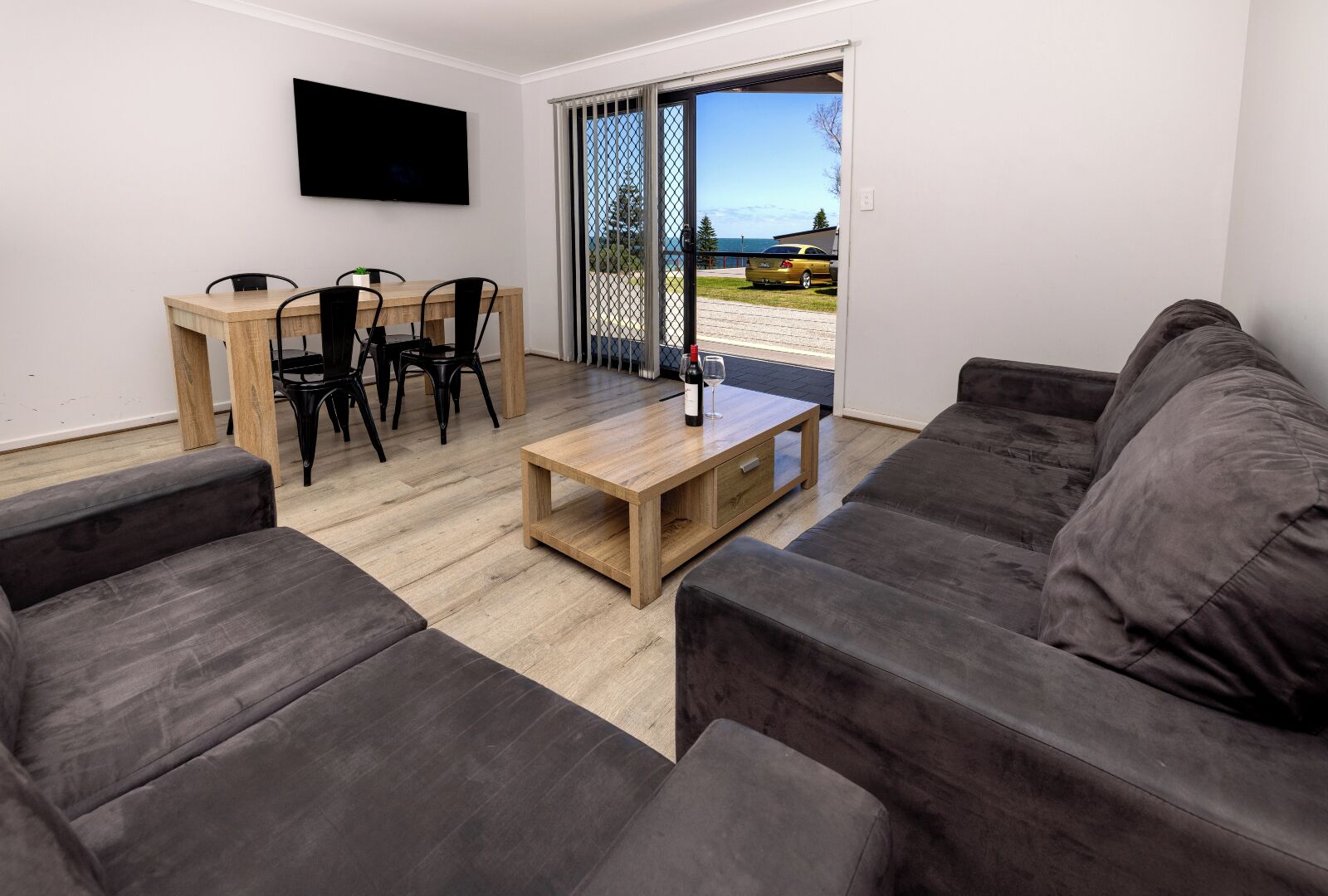 Un salon moderne comprenant un canapé, une table basse, une table à manger avec des chaises et un téléviseur fixé au mur.