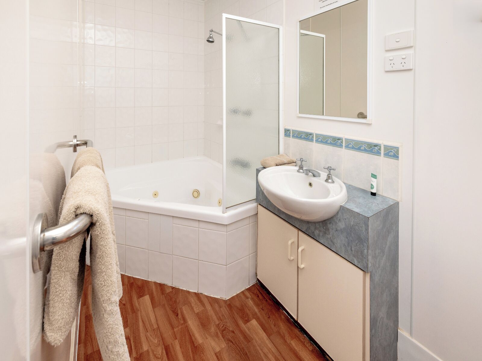 Une salle de bain avec une baignoire, un lavabo, un miroir et un porte-serviettes.
