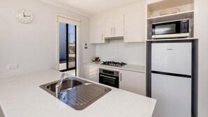 A modern kitchen with a stainless steel sink, a microwave, a built-in oven, and a refrigerator.