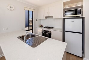 A modern kitchen with a stainless steel sink, a microwave, a built-in oven, and a refrigerator. - BIG4 Port Hughes Holiday Park (Port Hughes)