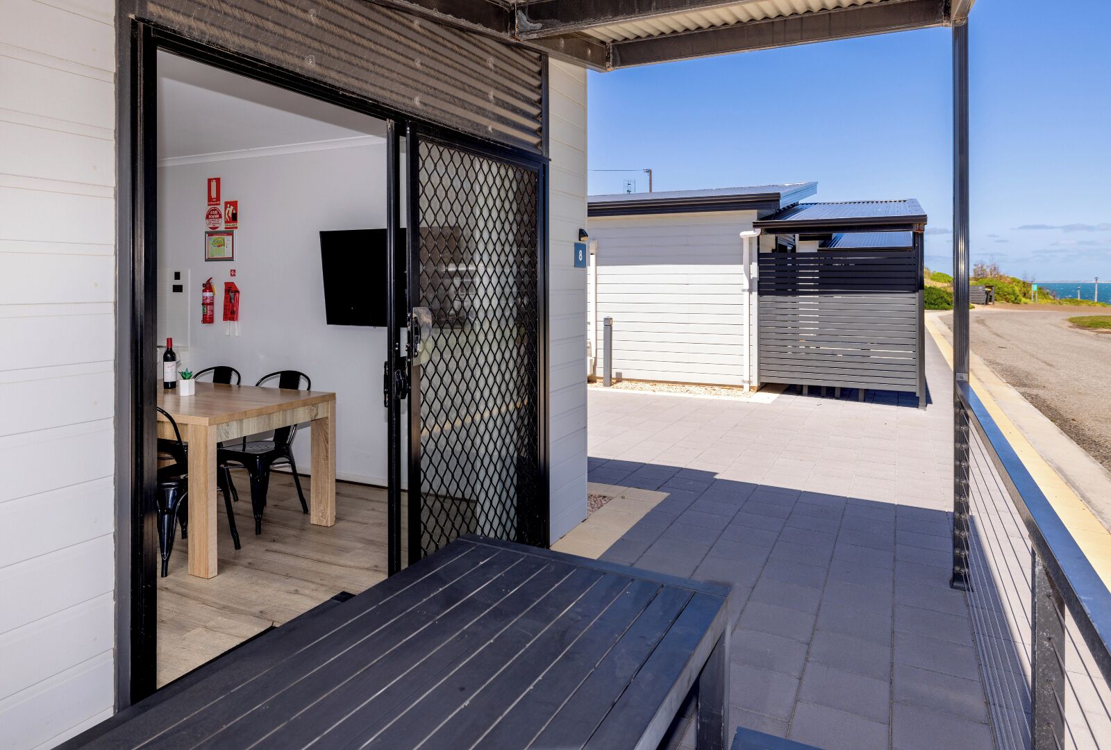 An open door leading to a room with a table and chairs, a fire extinguisher, and a television on the wall.