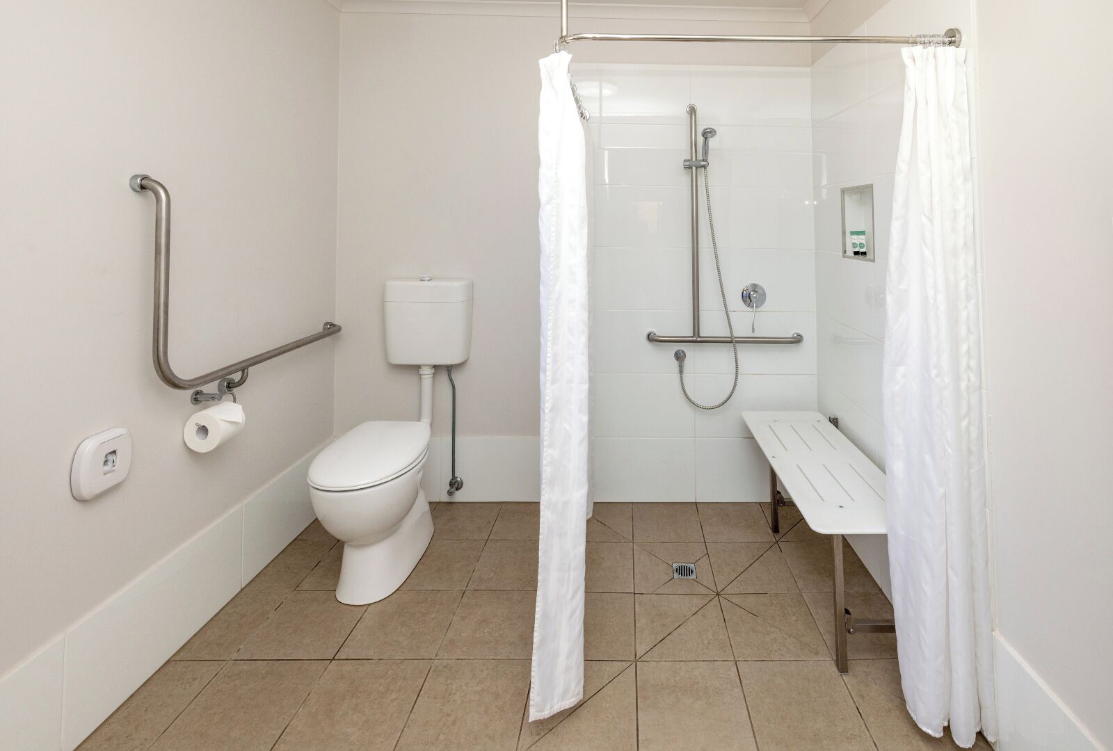 Een badkamer met toilet, bidet, douche en handgrepen.