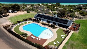 A modern building with a swimming pool, solar panels, and a view of the ocean.
