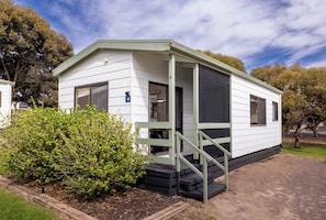 A small, single-story mobile home with a porch and steps leading to the entrance.